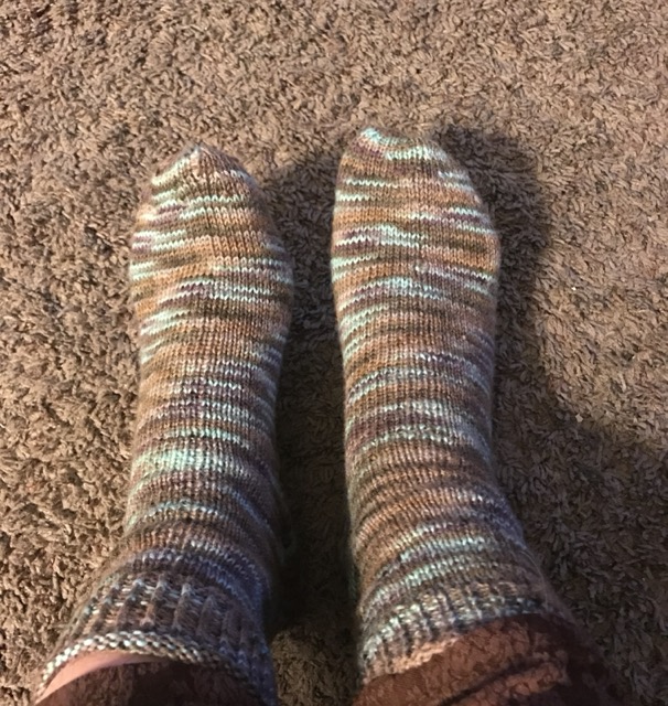 My first-ever pair of handknit socks, made in 2017, which are variegated with a range of brown and blue tones with some purple accents.