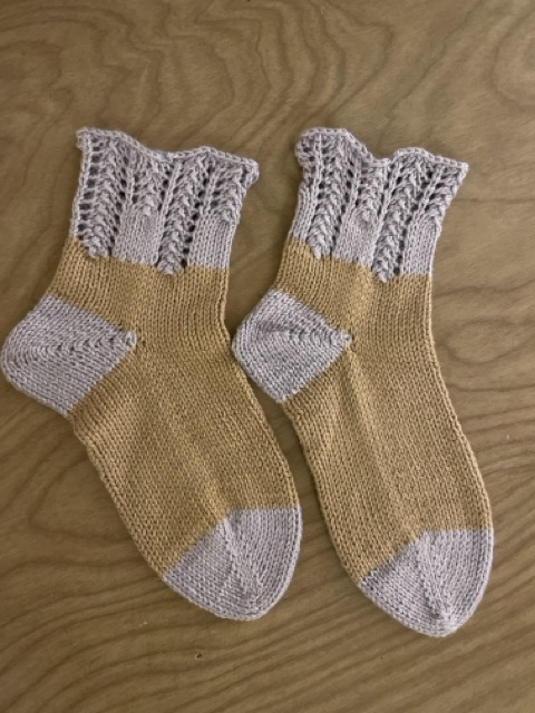 A pair of socks that are mostly brown, with light purple toes and light purple lace cuffs. I knitted these in 2021, using  a cotton-linen blend yarn for a close friend and fellow philsophy major who has a wool allergy.